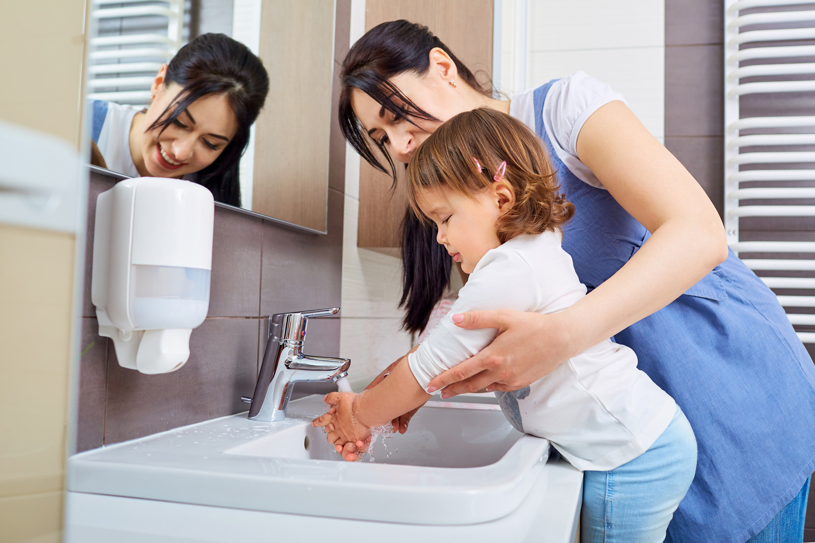 mãe e criança em uma banheiro, a mãe ajudando a criança a lavar a mão.  