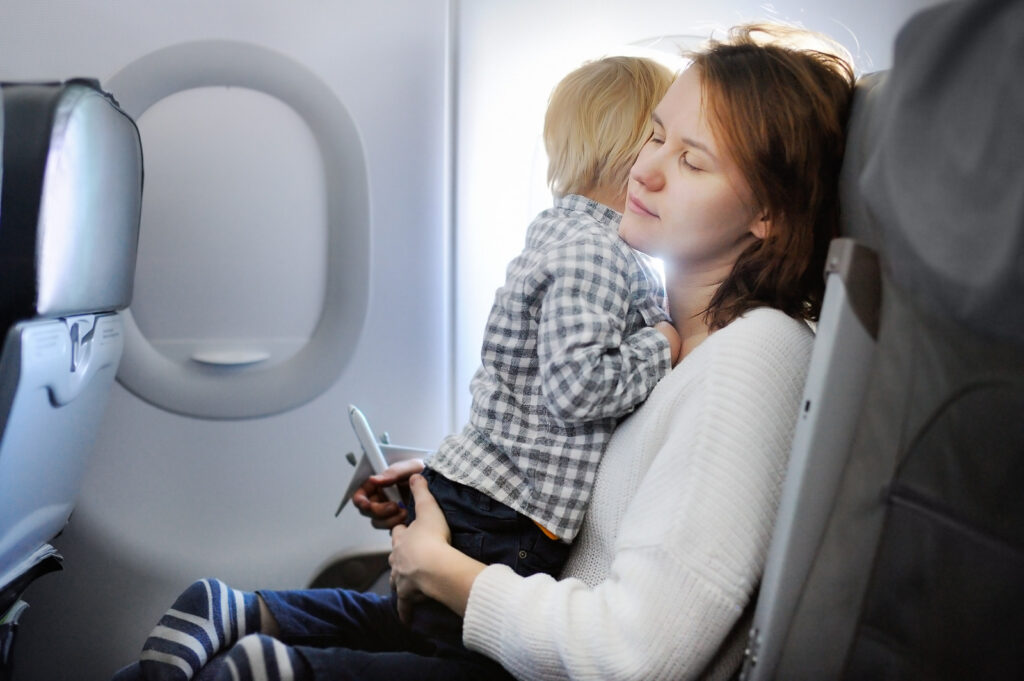 Mãe dentro do avião com uma criança no colo. 