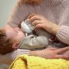 Babysitter feeding cute little child from bottle, artificial feeding accessories