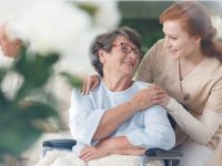 Cuidadora e uma idosa em uma cadeira de rodas