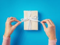 Mãos fazendo um nó para a caixinha de um presente